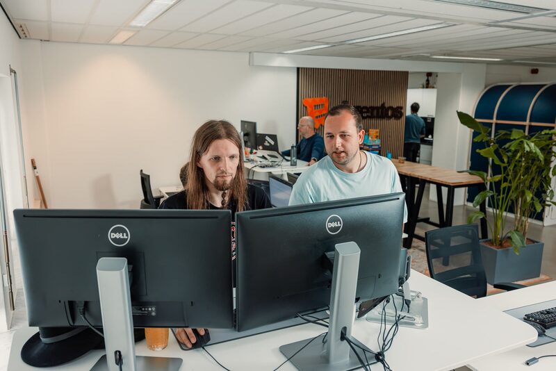 Twee collega's werken samen aan een bureau