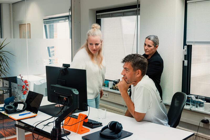 Collega's overleggen samen achter een scherm